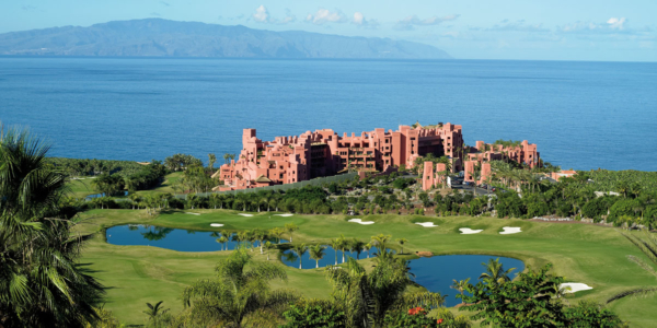 The Ritz-Carlton Abama Resort in Tenerife with golf course, palm trees and lake in front and sea behind