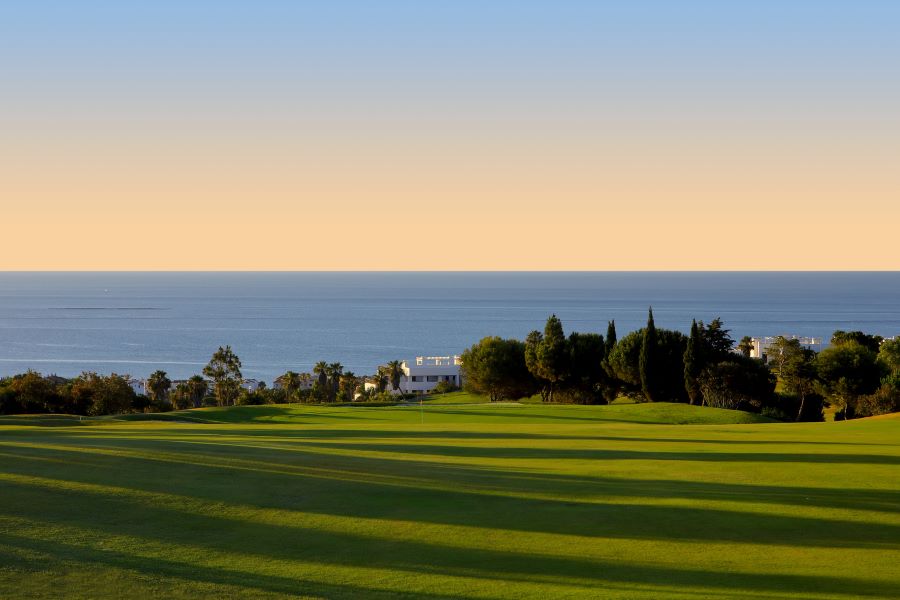 Hole 14 at Dona Julia Golf Club in Estepona with sea views and a sunset in the distance