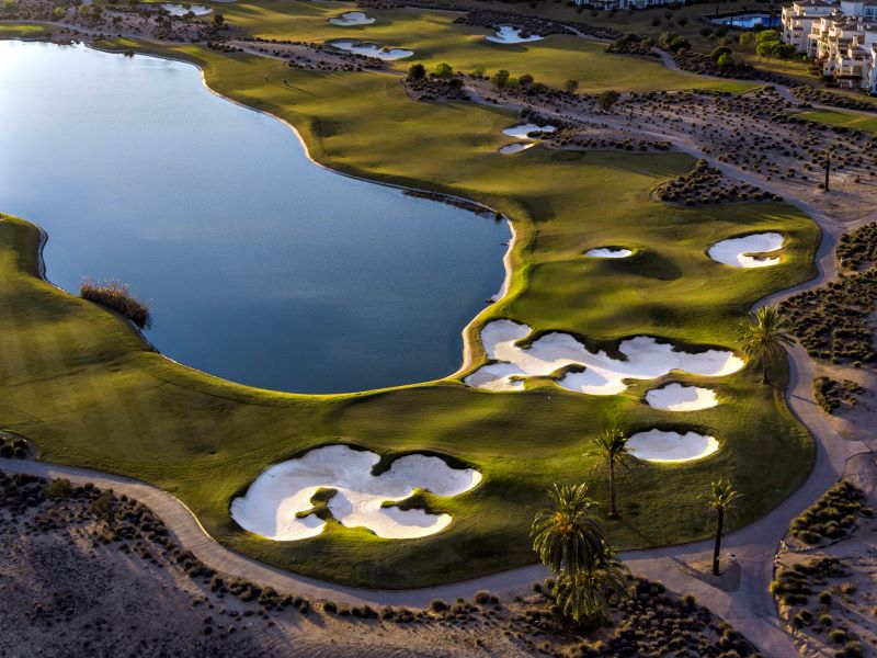 Hacienda Riquelme golf course with green fairway wrapping around blue lake