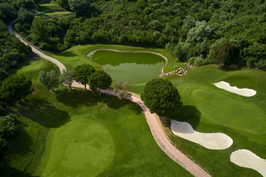 Lake between putting green and green trees at Higuerón Marbella Golf Resort