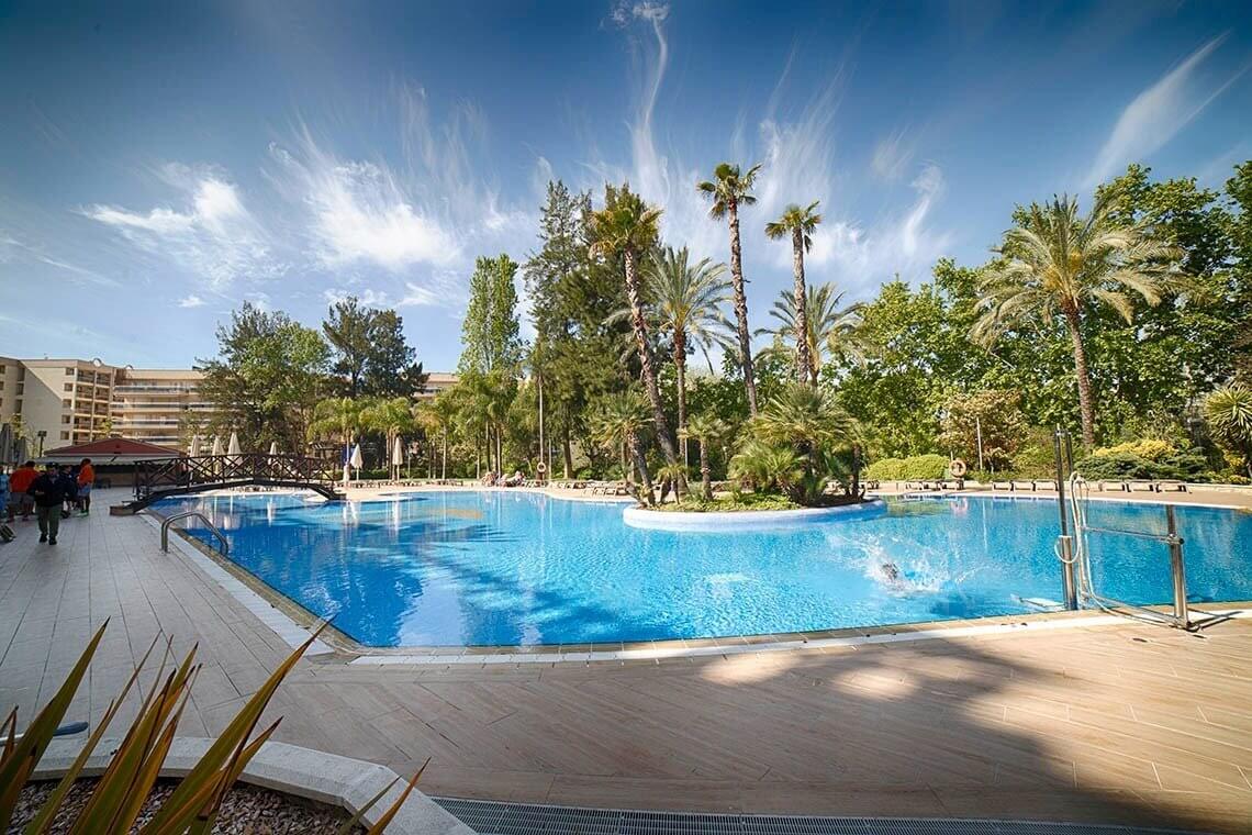 Outdoor swimming pool at Vila Romana hotel with trees in the distance