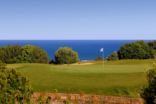Valle Romano golf course with pin in the foreground and blue sea in the background