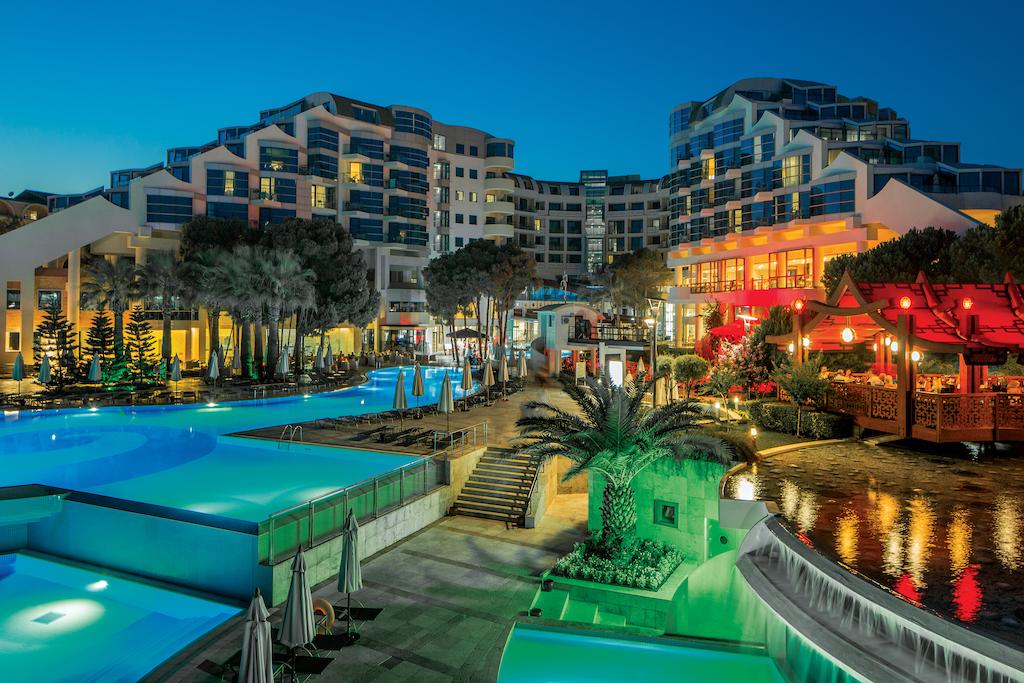 Cornelia Deluxe Resort in Belek at night with lights illuminating the outdoor swimming pool and bar