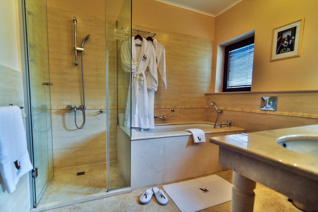 Bathroom at Thracian Cliffs Golf & Beach Resort with shower cubicle, bath tub, two robes, and sink