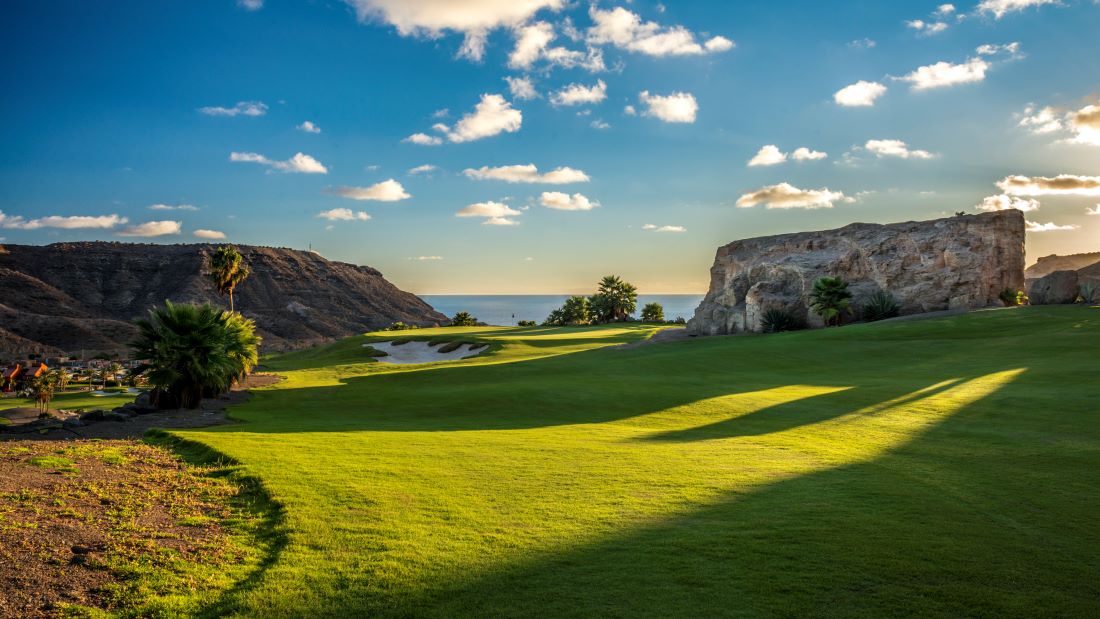 Anfi Tauro Golf Course in Gran Canaria, Spain, with large rocks, blue sky and see in the distance