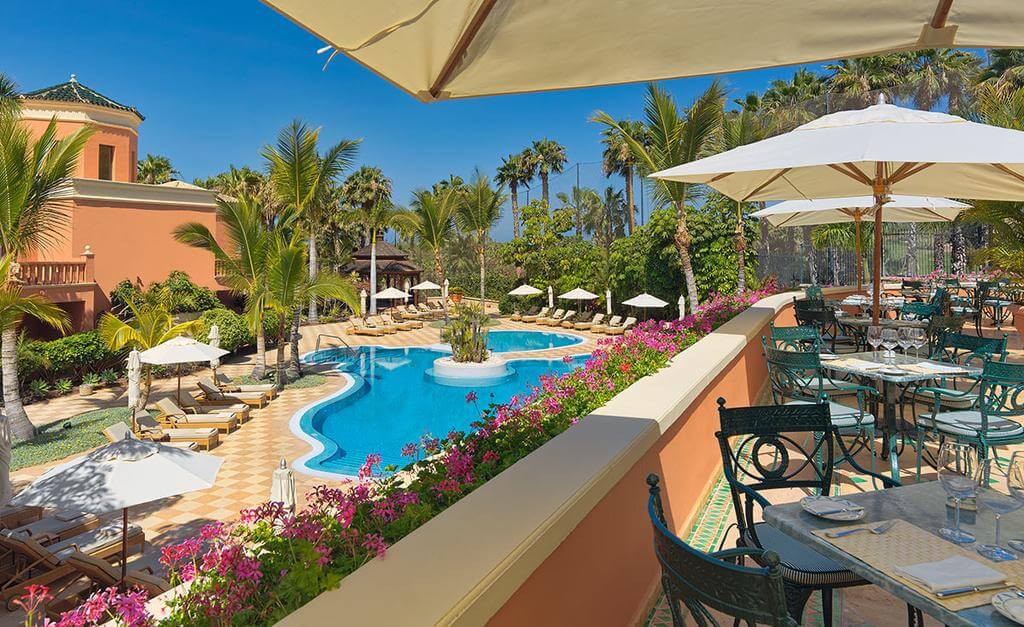 Outdoor swimming pool with sun loungers at Hotel Las Madrigueras Golf Resort And Spa with restaurant overlooking