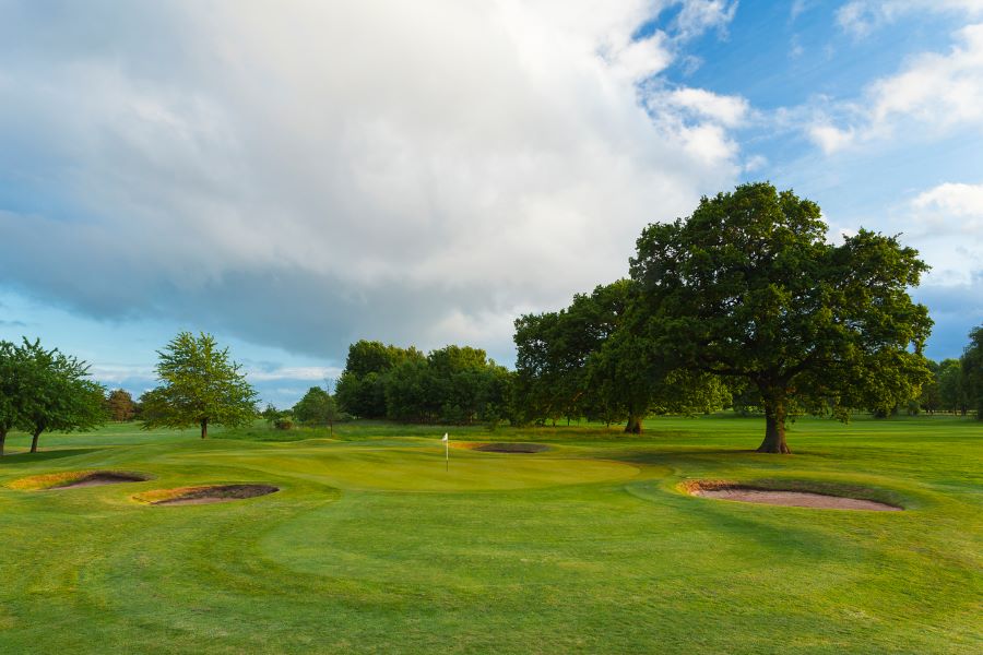 Large white cloud over the putting green with trees behind at Belton Woods Hotel, Spa And Golf Resort