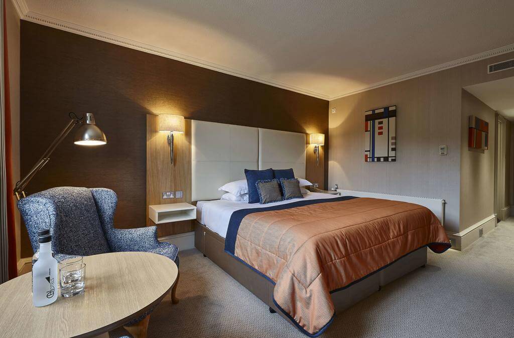Double bedroom with armchair and table at Oulton Hall Golf Hotel And Spa