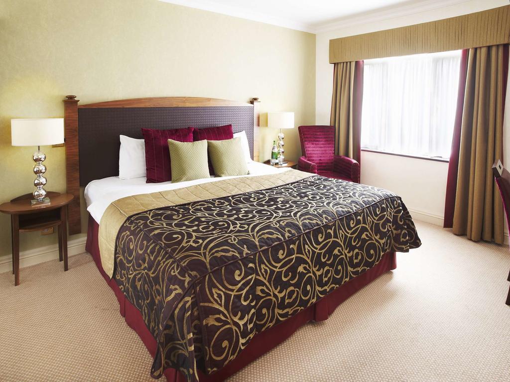 Double bedroom with armchair and bedside tables at Belton Woods