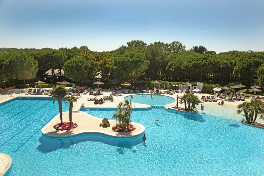 Swimming pool with palm trees overlooking the water at La Costa Golf and Beach Resort