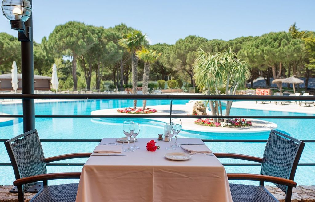 Restaurant with tables by the pool at La Costa Golf and Beach Resort