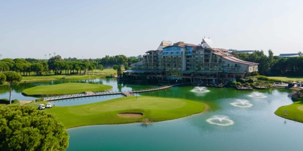Sueno Golf Hotel Belek from the air with the lake and bridge surrounding the golf course in the foreground