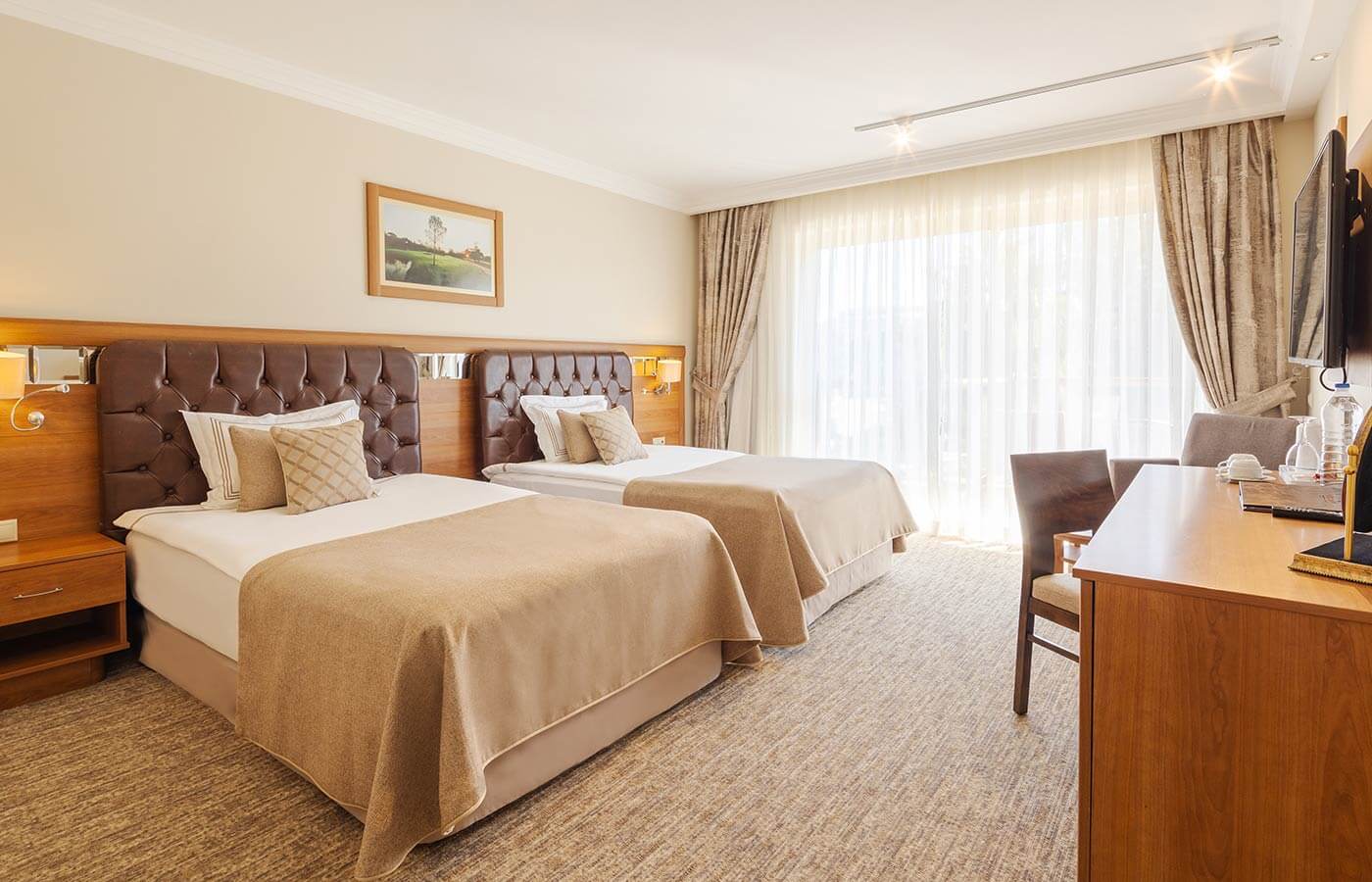 Twin bedroom with desk and wall mounted television at Sueno Golf Hotel Belek