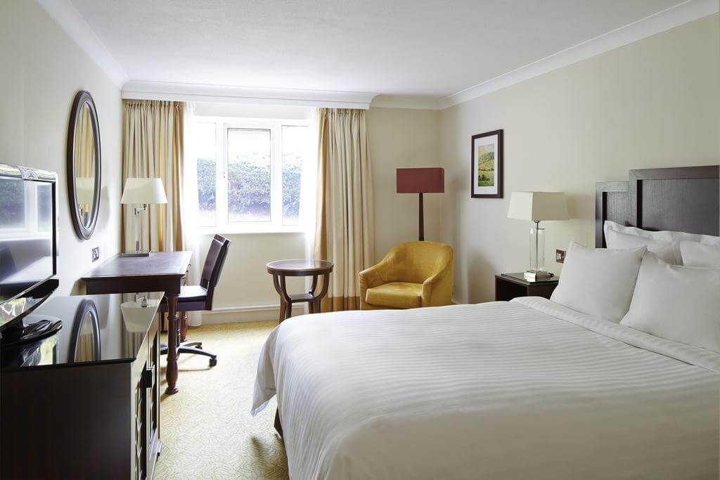 Bedroom with double bed, desk, television and armchair at Forest of Arden Marriott Hotel And Country Club