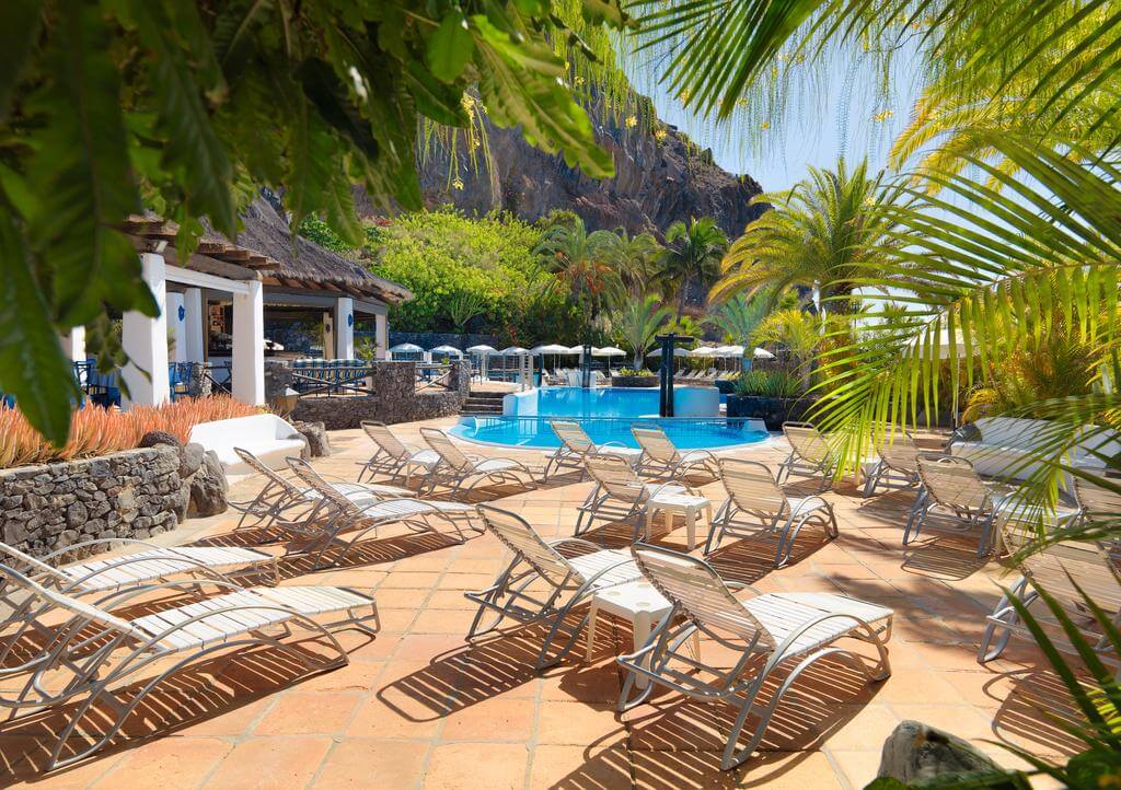 Sun loungers by the pool at Hotel Jardin Tecina with cliff face of La Gomera Island behind
