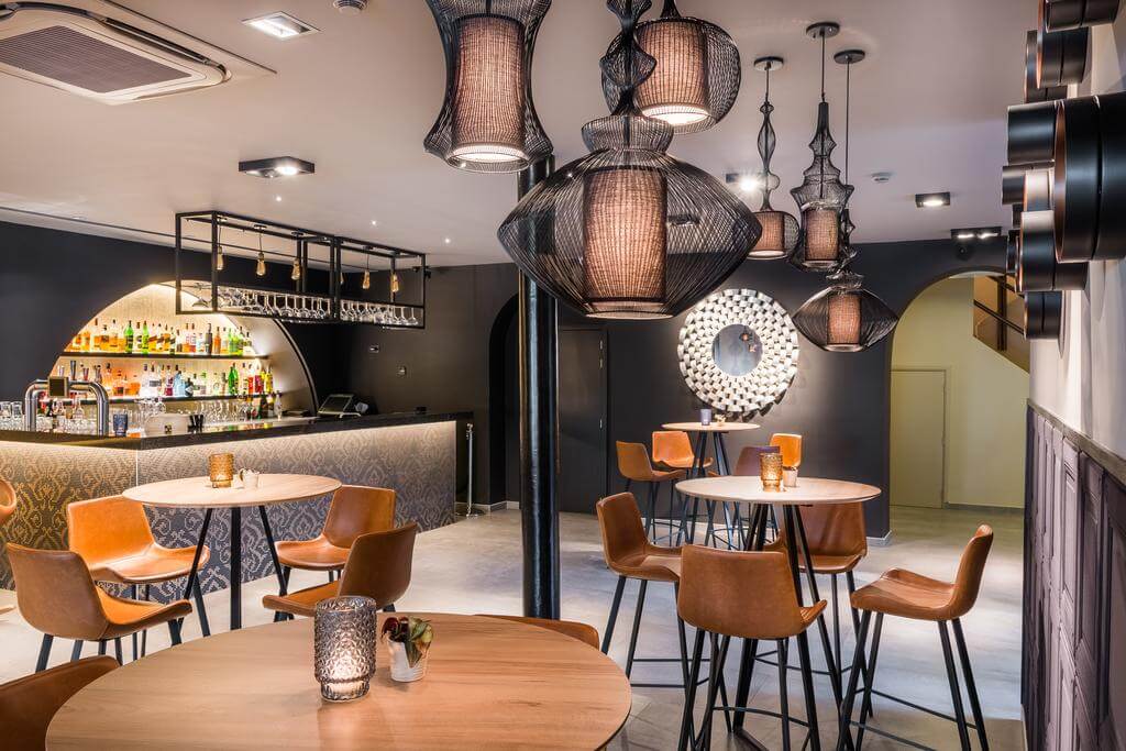 Martin's Chateau Du Lac bar with brown stools, wooden tables, alcoholic drinks behind bar, and lights hanging from ceiling