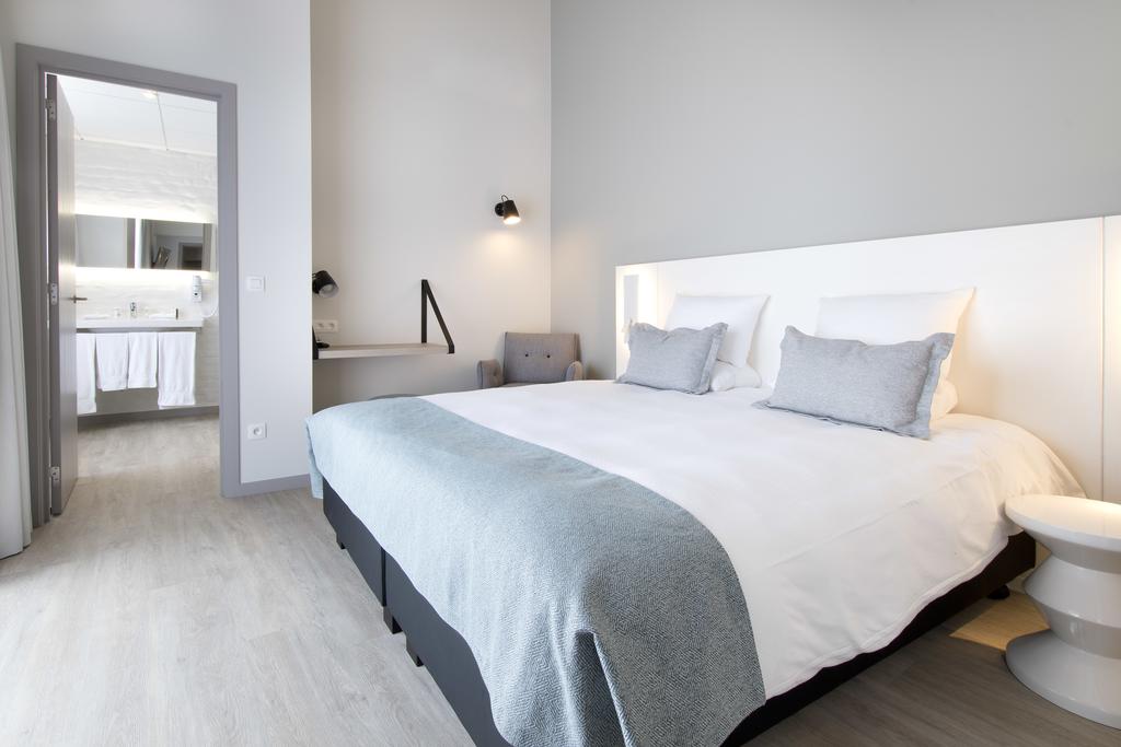 Double bed at Martin's Hotel Brugge with white bedside table, and private bathroom