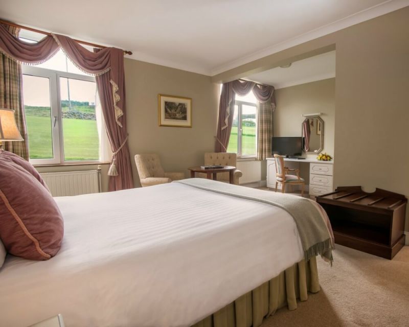 Double bedroom with television, armchairs, table and desk at Rosapenna Hotel And Golf Resort
