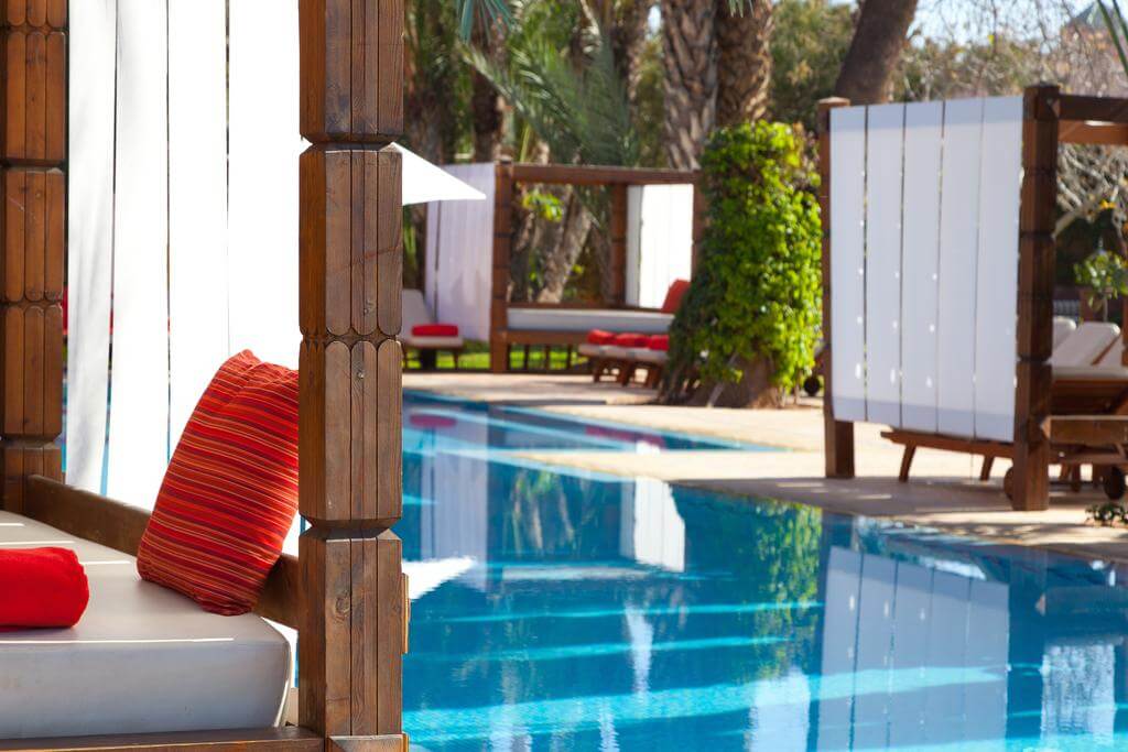 Hotel Sofitel Marrakech Lounge And Spa outdoor swimming pool with wooden sun loungers and red cushions