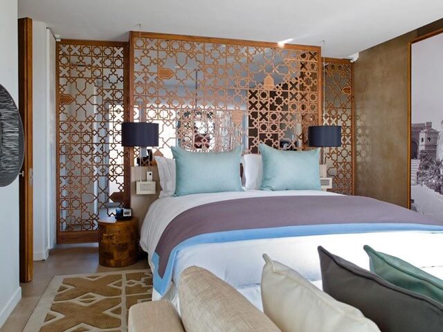 Double bed in Sofitel Essaouira Mogador Golf And Spa with green cushions on bed and two bedside lamps