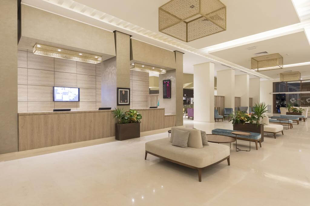 Reception desk Be Live Experience Marrakech Palmeraie with marble floor, seats, and plants in decorative boxes