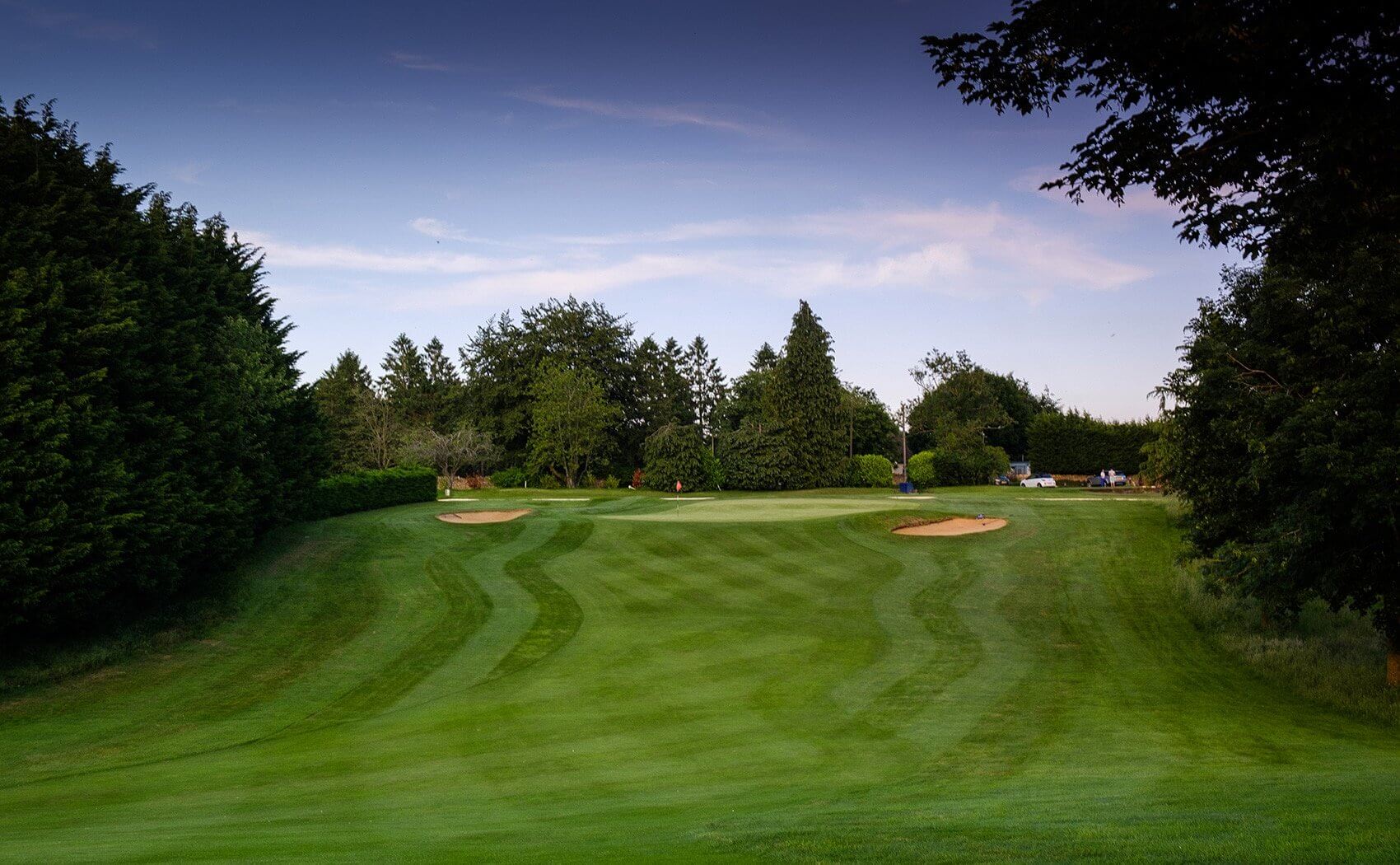 Tree lined fairway leading up to the green at Cotswolds Hotel Spa And Golf