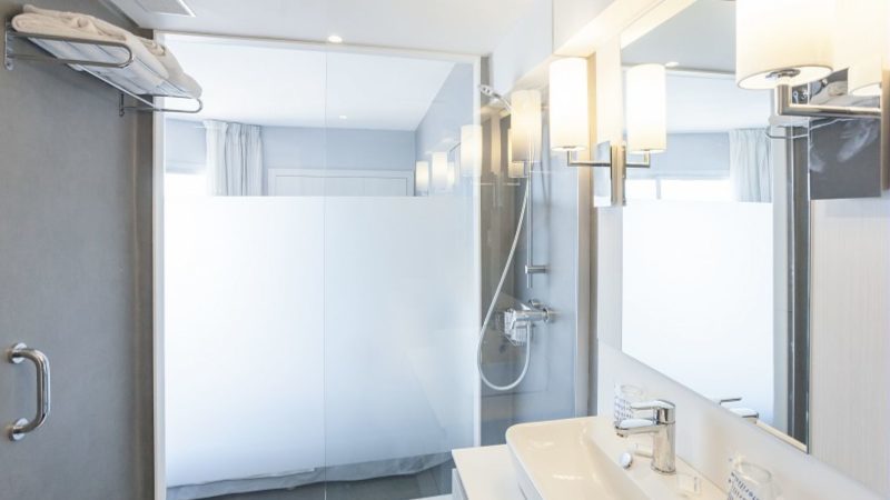 Bathroom at El Puerto Hotel with shower cubicle, sink, and mirror