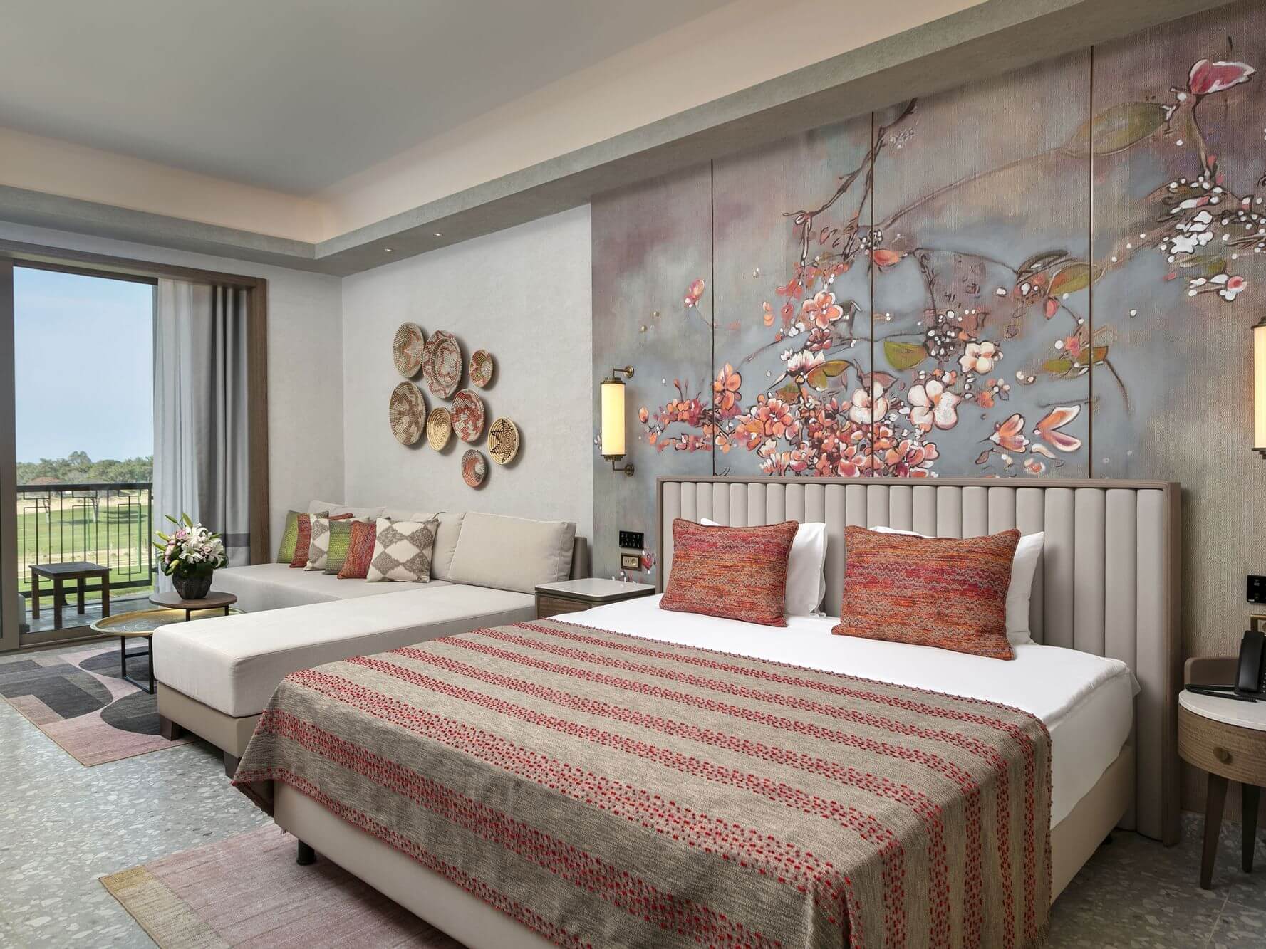 Bedroom at Cullinan Belek with double bed, seating area, floral wall, orange cushions and balcony