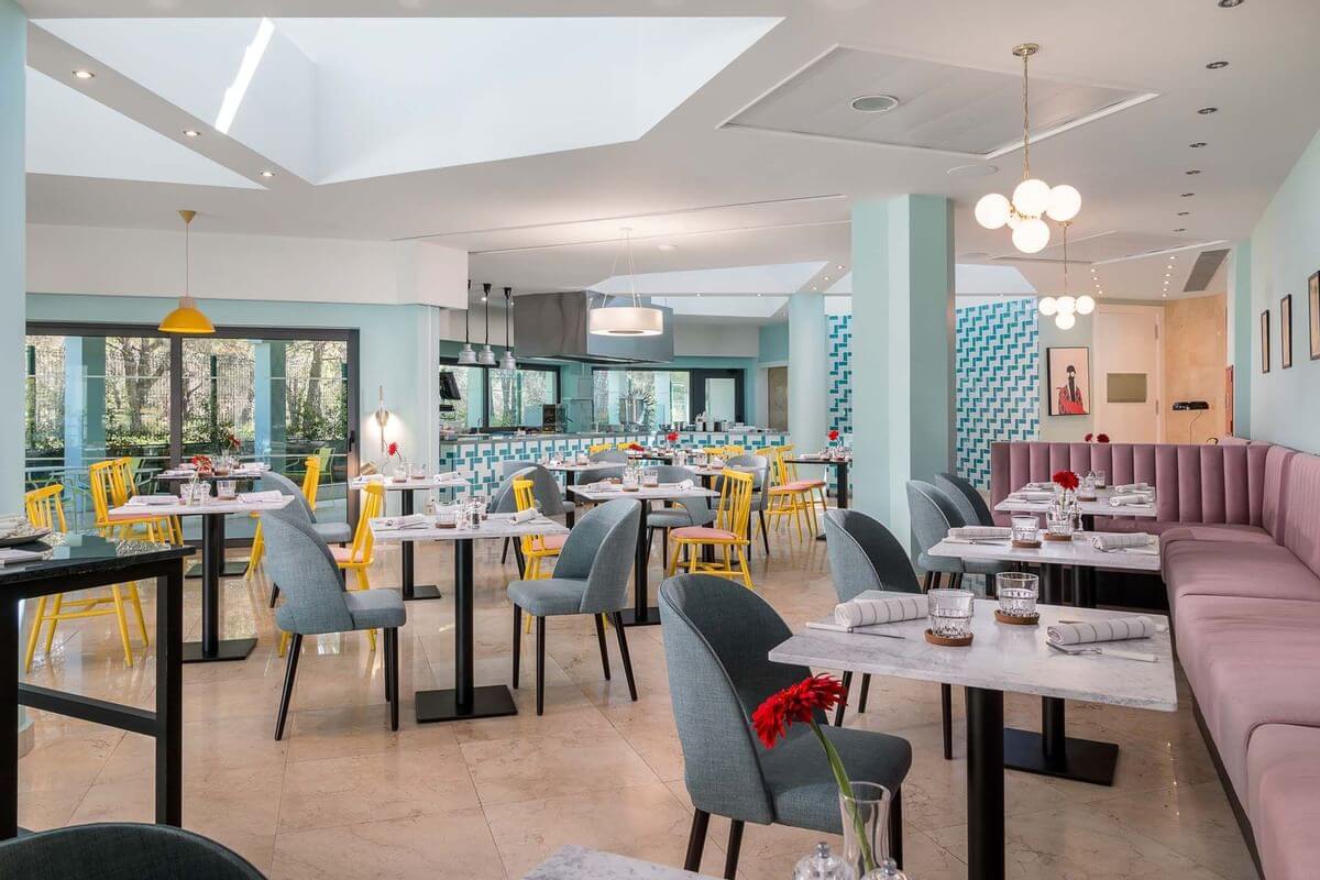 The Magnolia Restaurant with grey and yellow chairs, white tables, and wooden floor