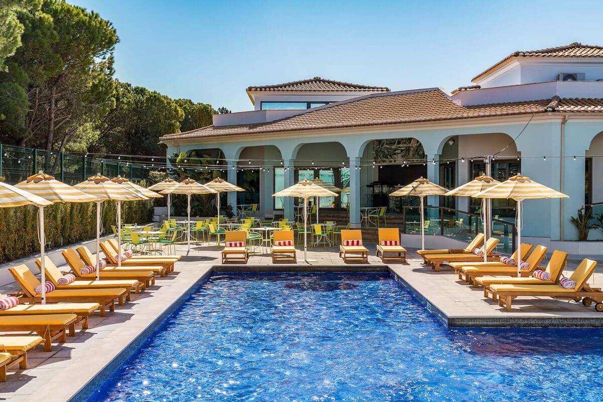 Outdoor heated swimming pool at The Magnolia Hotel with yellow sun loungers and parasols