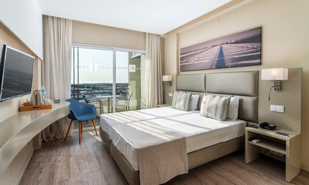 Double bedroom with balcony and blue chair at AP Maria Nova Lounge Hotel