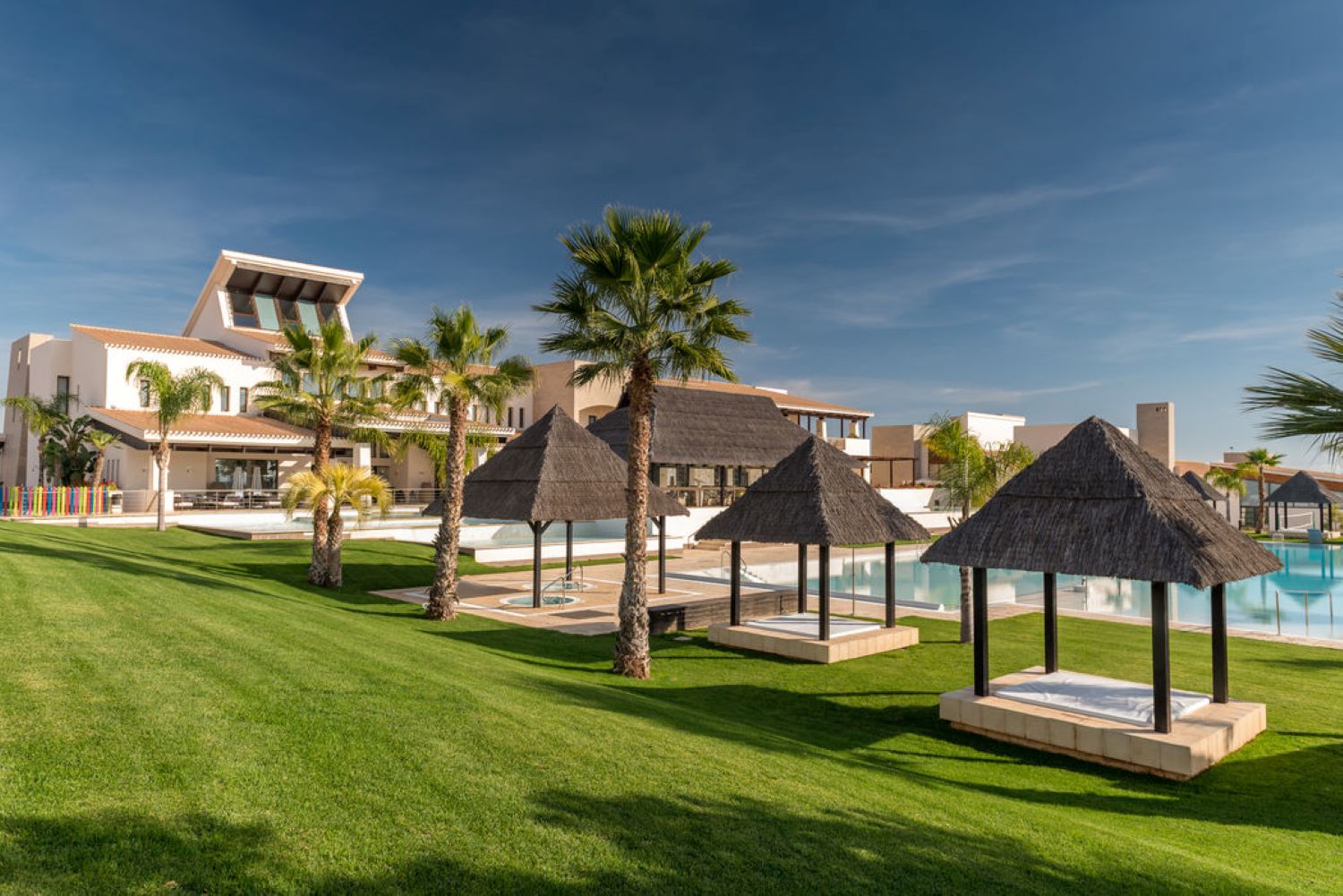 Outdoor area with huts by the swimming pool at Hacienda Del Alamo Golf Resort