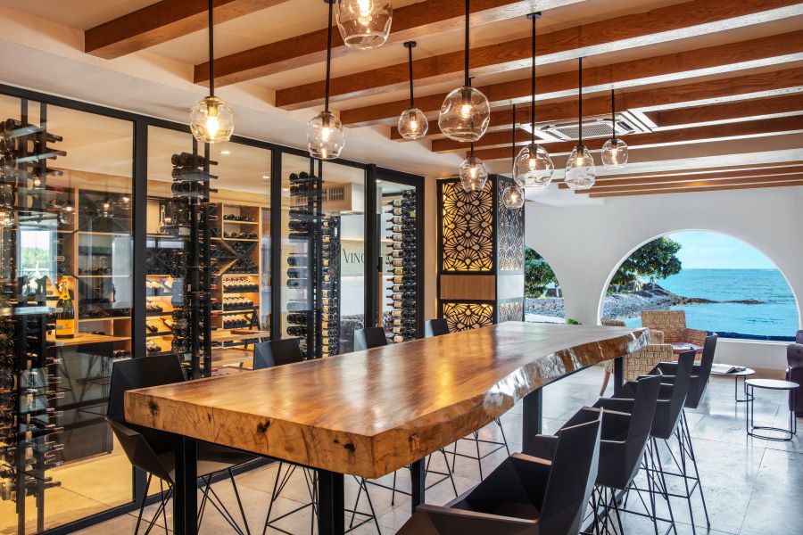 Large wooden table and stools with wine rack at Shangri-La Le Touessrok