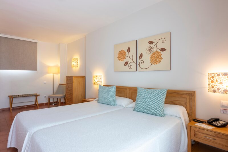 Twin beds with blue pillows and two pictures of flowers above the bed at GF Isabel